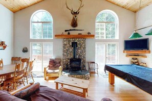 A cozy living room with a stone fireplace, wooden furniture, and a mounted animal head. - Papa's Mountain Retreat - Shaver Lake (Shaver Lake)