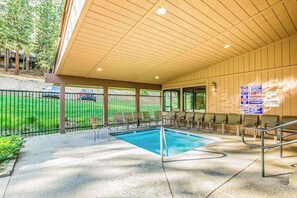 An indoor swimming pool with a covered area, chairs, and a view of a golf course. - Lake Therapy - Huntington Lake (Lakeshore)