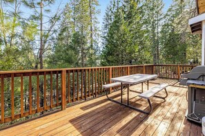 Eine Terrasse im Freien mit Holzgeländer, Picknicktisch und Grill.