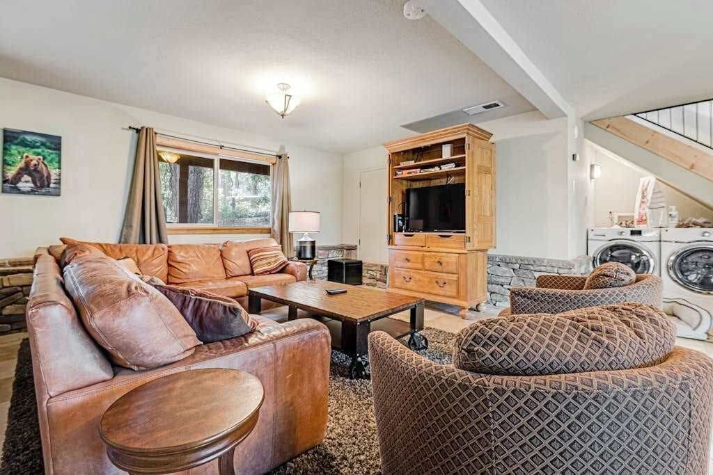 A cozy living room with a sofa, armchairs, a coffee table, and a television.