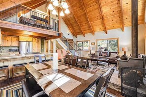 A spacious interior with a high ceiling, a dining area, a living room, and a fireplace. - Majestic Mountain - Big Trees Village (Dorrington)