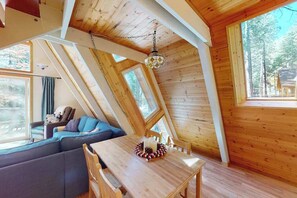 Ein Blockhaus-Interieur mit Esstisch, Sofa und einer Pendelleuchte.