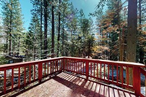Eine Holzterrasse mit roter Geländer, mit Blick auf ein bewaldetes Gebiet.