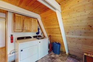 Ein Waschraum mit Holzausstattung, einer Waschmaschine, einem Trockner und einem Feuerlöscher.