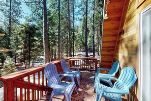 Eine Holzterrasse mit Adirondack-Stühlen, umgeben von hohen Kiefern.