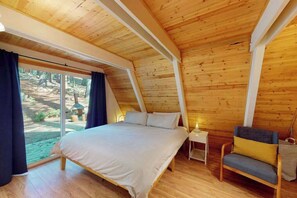 Ein Schlafzimmer mit einem Bett, einem Sessel, einem Nachttisch und einem großen Fenster.