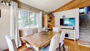 Un comedor con una mesa y sillas de madera, un televisor y una escalera.