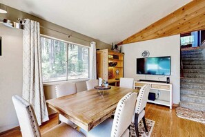 Ein Essbereich mit Holztisch und -stühlen, einem Fernseher und einer Treppe.