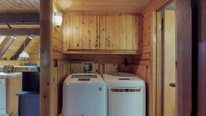 Una cucina compatta con mobili in legno, un lavandino e due elettrodomestici bianchi, probabilmente una lavatrice e un'asciugatrice.