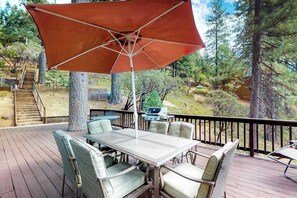 Una terraza con mesa y sillas, una parrilla y una escalera que lleva a un nivel superior.