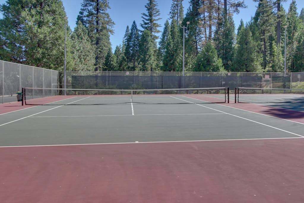 Un court de tennis en plein air, entouré d’une clôture et d’arbres.