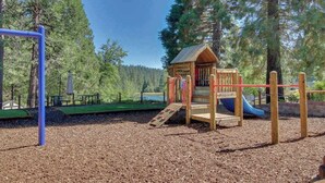 Un'area giochi con una casetta di legno, scivoli e una struttura per arrampicarsi.
