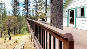 A wooden deck with outdoor furniture, surrounded by a forest.