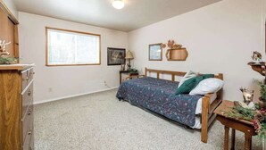 Ein Schlafzimmer mit Bett, Kommode, Fenster und Nachttisch.