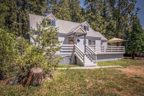 A cabin with a wooden deck, a staircase, and a porch. - Sparrow Cove - East Village (Shaver Lake)