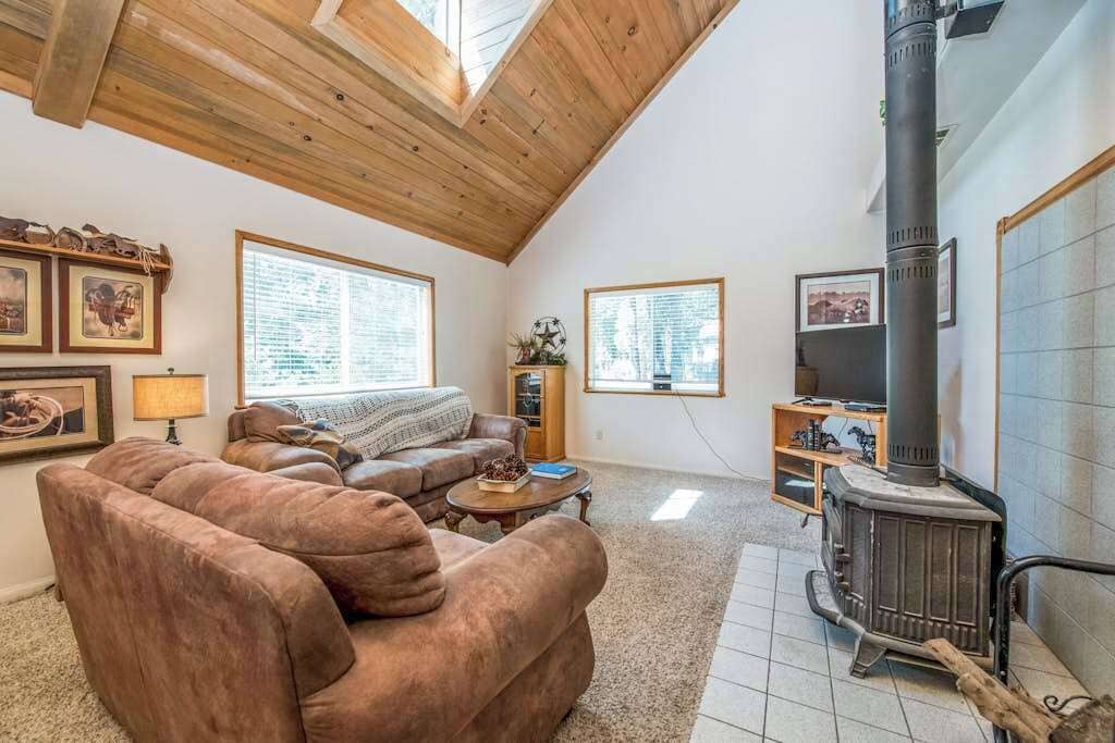 A cozy living room with a fireplace, a sofa, a coffee table, and a window.