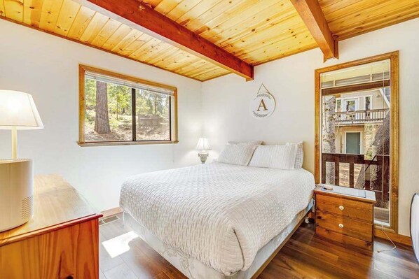 Una camera da letto con un letto grande, un comodino, una cassettiera, una finestra e vista sul balcone.