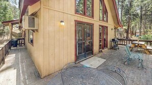 Eine Holzhütte mit einer überdachten Veranda, Sitzgelegenheiten im Freien und einem großen Fenster.