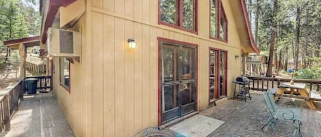 Eine Holzhütte mit einer überdachten Veranda, Sitzgelegenheiten im Freien und einem großen Fenster.
