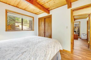 A bedroom with a bed, a window, and a wooden door. - Tranquility In The Woods - Blue Lake Springs (Arnold)