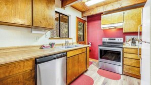 Eine kleine Küche mit Holzschränken, einem Geschirrspüler, einem Backofen und einem Kühlschrank.