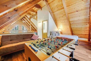 Un'accogliente stanza con un tavolo da calcio, un divano e un letto.