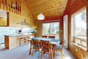 Ein Holzblockhaus-Interieur mit Essbereich, Küche und großen Fenstern.