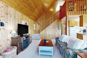 Ein Holzinnenraum mit einer Couch, einem Fernseher und einer Treppe.