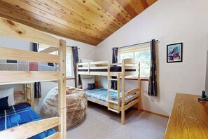 Quarto com beliche, um cadeirão de fibra e uma escrivaninha.