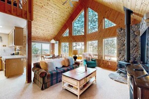 Un amplio salón con techo alto, ventanas grandes, chimenea y un rincón de estar acogedor.