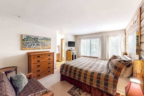 Ein Schlafzimmer mit Bett, Kommode, Fernseher und Kunstwerken.