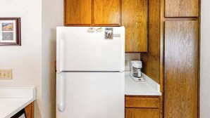 A kitchen with wooden cabinets, a white refrigerator, and a coffee maker on the countertop. - Big Mountain, Little Condo - Huntington Lake (Lakeshore)
