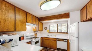 A kitchen with wooden cabinets, a white countertop, a stove, a sink, and a refrigerator. - Big Mountain, Little Condo - Huntington Lake (Lakeshore)