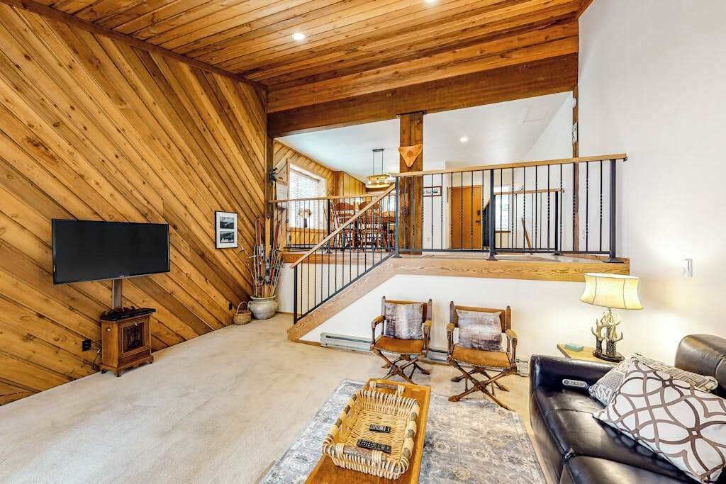Un intérieur en bois avec un escalier, un téléviseur à écran plat et un coin salon.