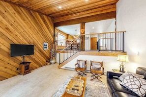 A wooden interior with a staircase, a flat-screen TV, and seating area.