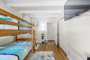 Ein Schlafzimmer mit Etagenbetten, einer Tür, einem Spiegel und einem Flur, der zu einem Schrank führt.