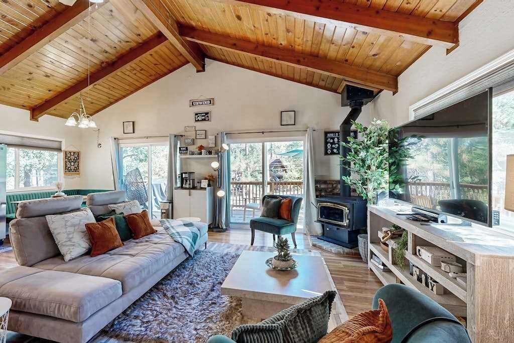 A spacious living room with a high ceiling, a sofa set, a coffee table, and a television.