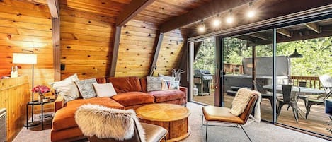 A cozy interior with a wooden ceiling, a sofa, a chair, and a round coffee table.