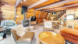 A cozy, wood-paneled room with a fireplace, a television, and a dining area. - Heavenly Daze - Meadowmont (Arnold)