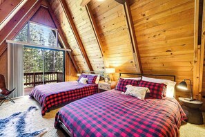 Une chambre confortable avec deux lits, une grande fenêtre et un plafond en bois.