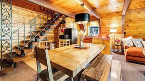 A wooden interior with a dining table, chairs, a sofa, a staircase, and a kitchen area. - Heavenly Daze - Meadowmont (Arnold)