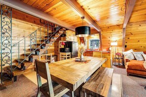 Ein Holzinnenraum mit einem Esstisch, Stühlen, einer Couch, einer Treppe und einer Küchenzeile.