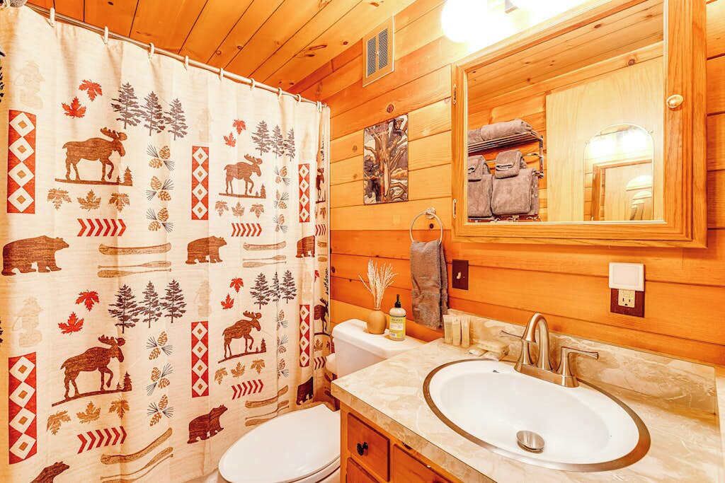 Baño con dos lavamanos, un espejo y cortina de ducha con estampados de animales.