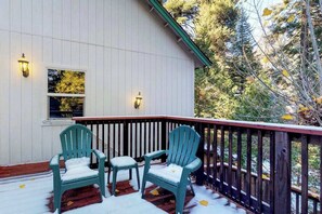 A covered porch with Adirondack chairs and a wooden railing. - New England Cottage - Ockenden Ranch (Shaver Lake)