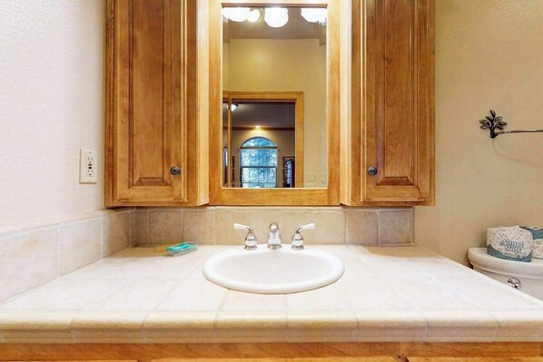 A bathroom with a wooden vanity, a white sink, and a mirror above it. - New England Cottage - Ockenden Ranch (Shaver Lake)