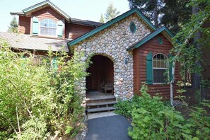 A rustic cabin with a stone archway entrance, wooden siding, and a small porch. - New England Cottage - Ockenden Ranch (Shaver Lake)