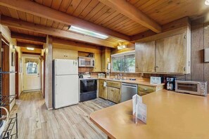 A compact kitchen with wooden cabinets, a refrigerator, microwave, oven, and dishwasher.