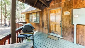 A wooden cabin with a porch, a grill, and a door with a window. - The Arrow House - Big Tree Village (Camp Connell)