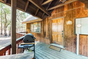 Eine Holzhütte mit Veranda, Grill und einer Tür mit Fenster.