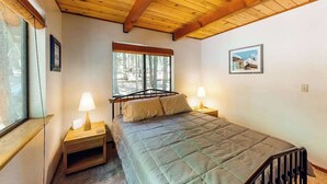 A bedroom with a bed, two bedside tables, a window, and a wooden ceiling. - The Arrow House - Big Tree Village (Camp Connell)